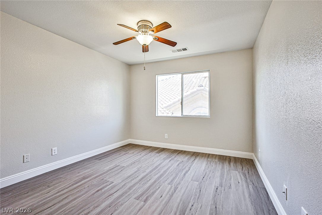 1828 Dolce Drive, Las Vegas, NV 89134 A quiet bedroom with plank flooring and a modern ceiling fan for comfortable living.