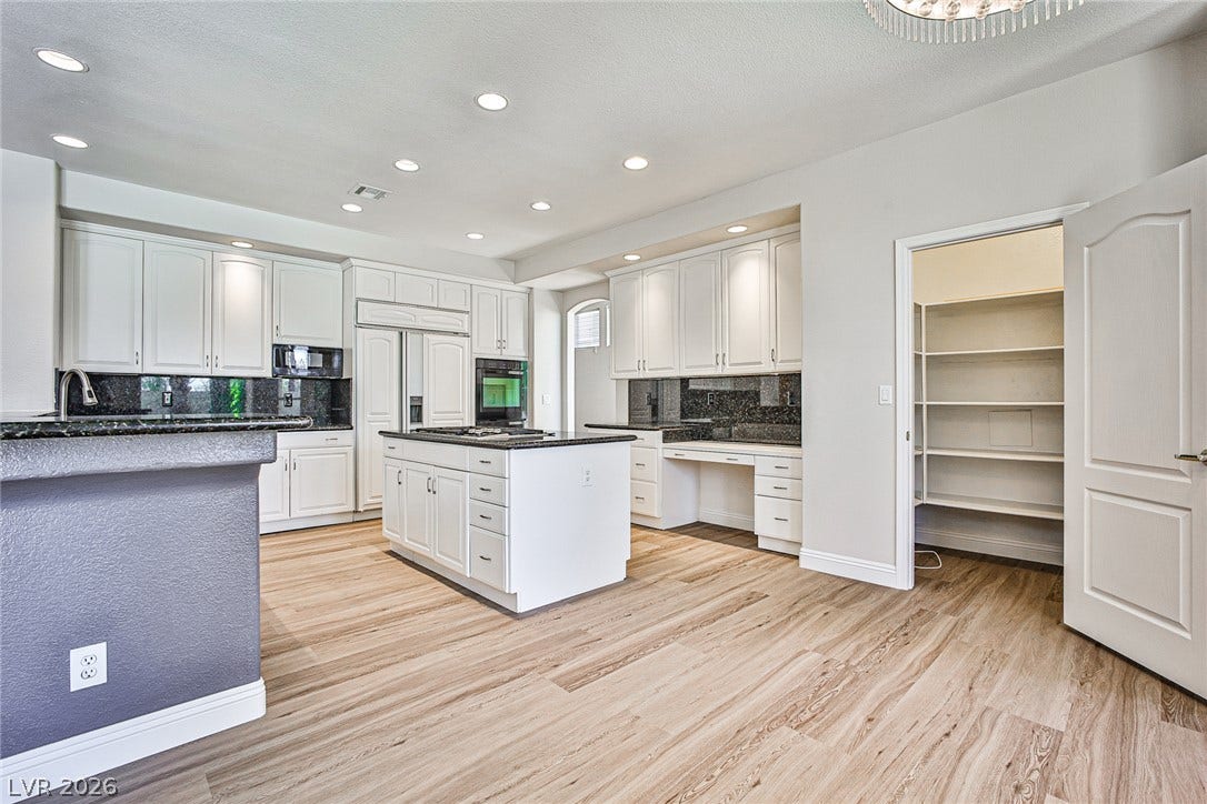 1828 Dolce Drive, Las Vegas, NV 89134 A well-appointed kitchen features a large center island and abundant white cabinetry with dark granite countertops.