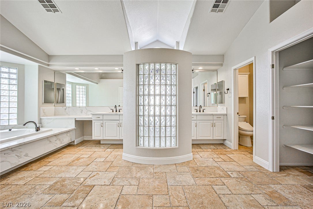 1828 Dolce Drive, Las Vegas, NV 89134 A spacious bathroom offers dual vanities, a luxurious soaking tub, and a separate water closet.