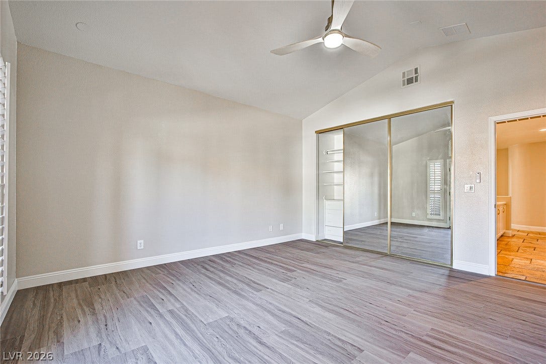 1828 Dolce Drive, Las Vegas, NV 89134 Lofty ceilings and sleek wood-look flooring enhance this inviting bedroom, featuring mirrored closet doors for added allure.