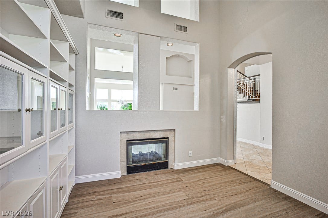 1828 Dolce Drive, Las Vegas, NV 89134 Built-in shelving and a fireplace anchor this naturally illuminated room with inviting wood flooring.
