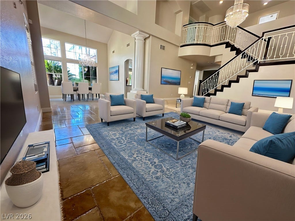 1828 Dolce Drive, Las Vegas, NV 89134 Virtual photo,A grand, naturally illuminated living room featuring a double-height ceiling and a sweeping staircase.
