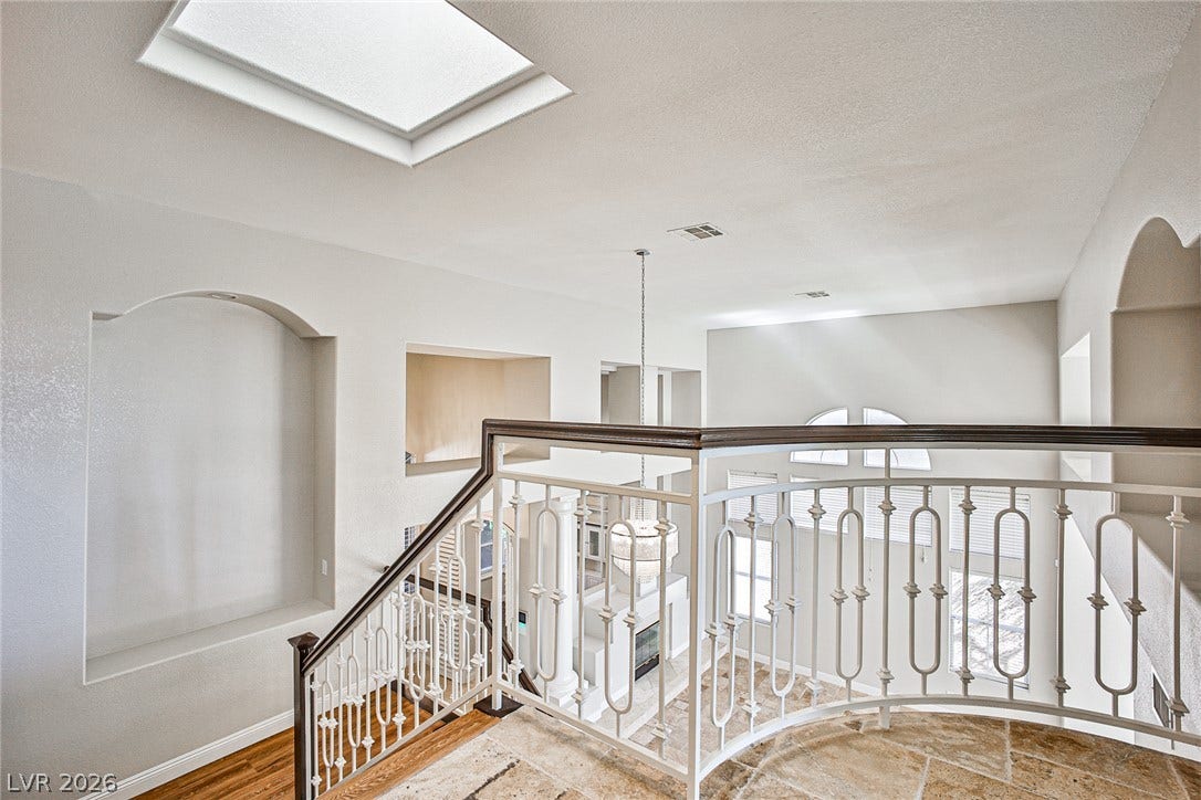 1828 Dolce Drive, Las Vegas, NV 89134 Natural light streams through a skylight above a grand staircase with intricate wrought iron railings.