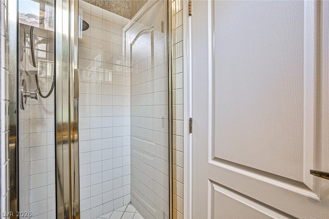 1828 Dolce Drive, Las Vegas, NV 89134 Tiled shower enclosure with clear glass doors and classic white paneling.