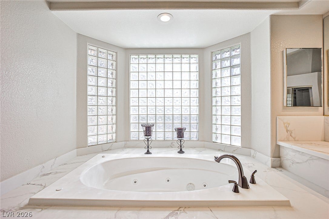 1828 Dolce Drive, Las Vegas, NV 89134 Indulge in a tranquil soak within this well-appointed bathroom featuring a built-in tub and privacy glass block windows.