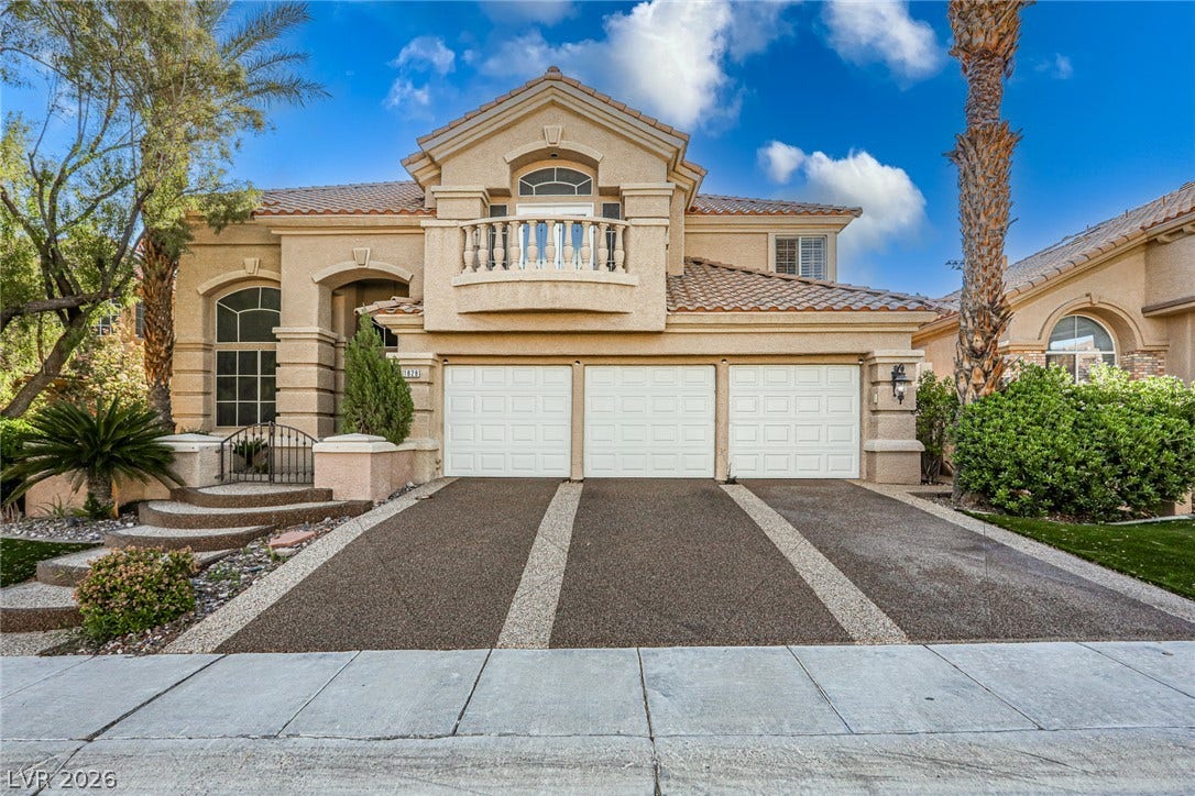 1828 Dolce Drive, Las Vegas, NV 89134 A grand Mediterranean-style home presents an inviting entry with a decorative balcony and a three-car garage.