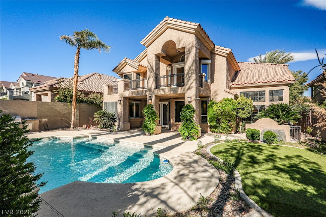 1828 Dolce Drive, Las Vegas, NV 89134 A terracotta-roofed residence with multiple balconies overlooks a sun-drenched pool and lush, manicured lawn.