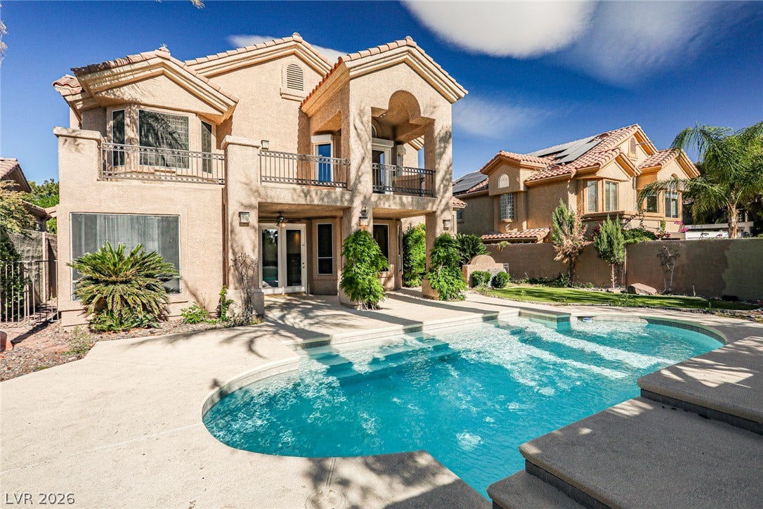 1828 Dolce Drive, Las Vegas, NV 89134 An inviting backyard oasis awaits with a sparkling pool and a Mediterranean-inspired home featuring multiple balconies.