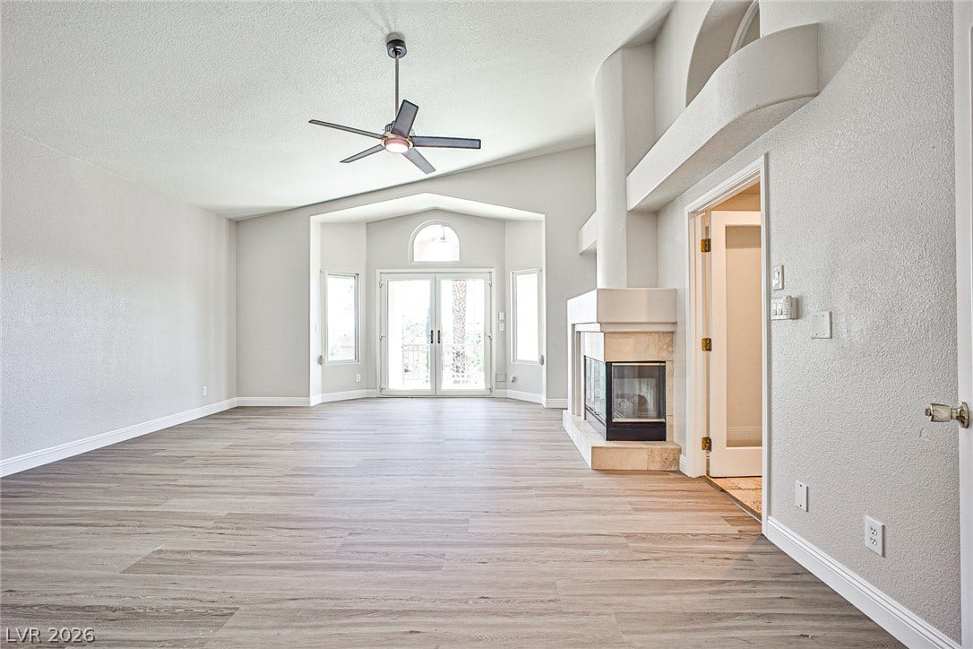 1828 Dolce Drive, Las Vegas, NV 89134 A spacious living area features high ceilings, a fireplace, and light wood flooring leading to French doors.