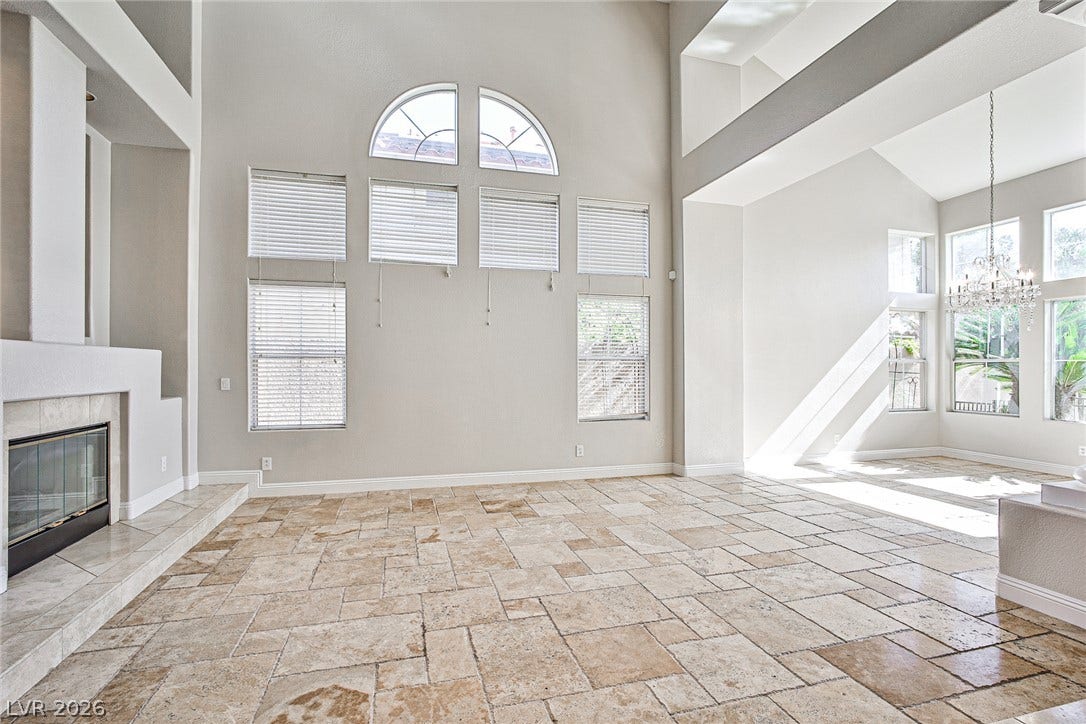 1828 Dolce Drive, Las Vegas, NV 89134 Sun-filled great room with soaring vaulted ceilings, a cozy fireplace, and natural stone tile flooring.