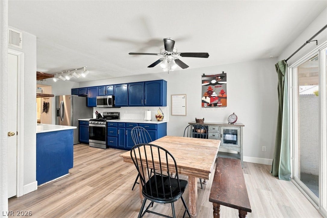 505 Rafkin Place, Henderson, NV 89052 Bold blue cabinetry brightens this kitchen and dining area, featuring sleek stainless steel appliances and durable hardwood flooring.