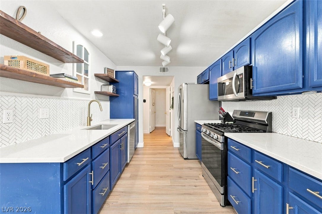 505 Rafkin Place, Henderson, NV 89052 Kitchen with sleek white quartz counters, stylish blue cabinetry, and modern stainless steel appliances.