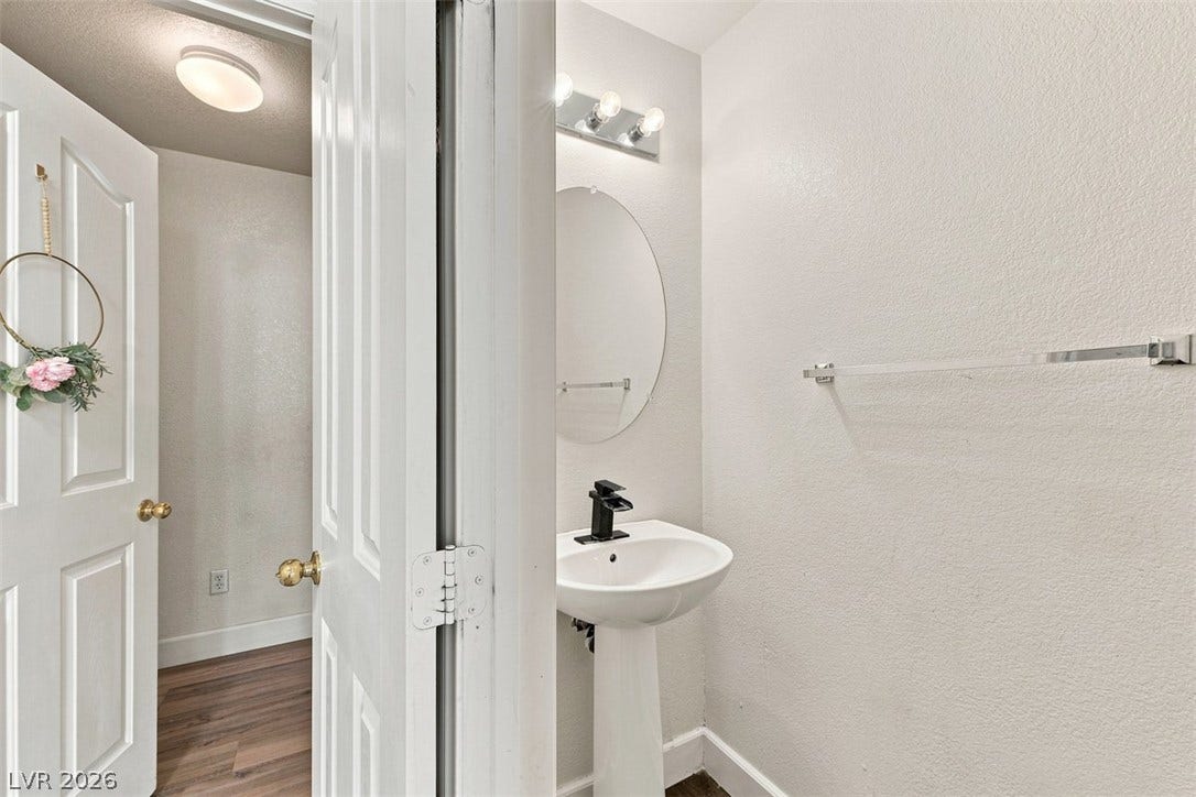 505 Rafkin Place, Henderson, NV 89052 A compact powder room with a sleek pedestal sink and contemporary lighting offers functional elegance.