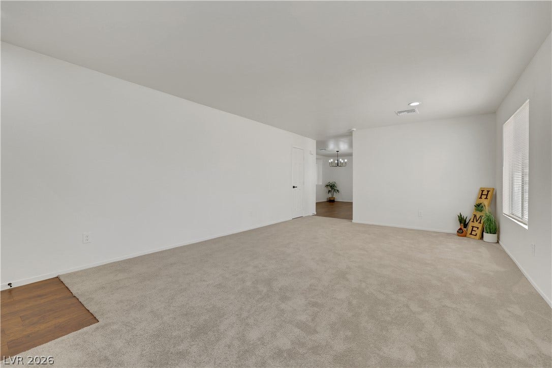 648 Moonlight Mesa Drive, Henderson, NV 89011 An open living area with plush carpeting transitions to warm wood flooring, offering versatile design possibilities.