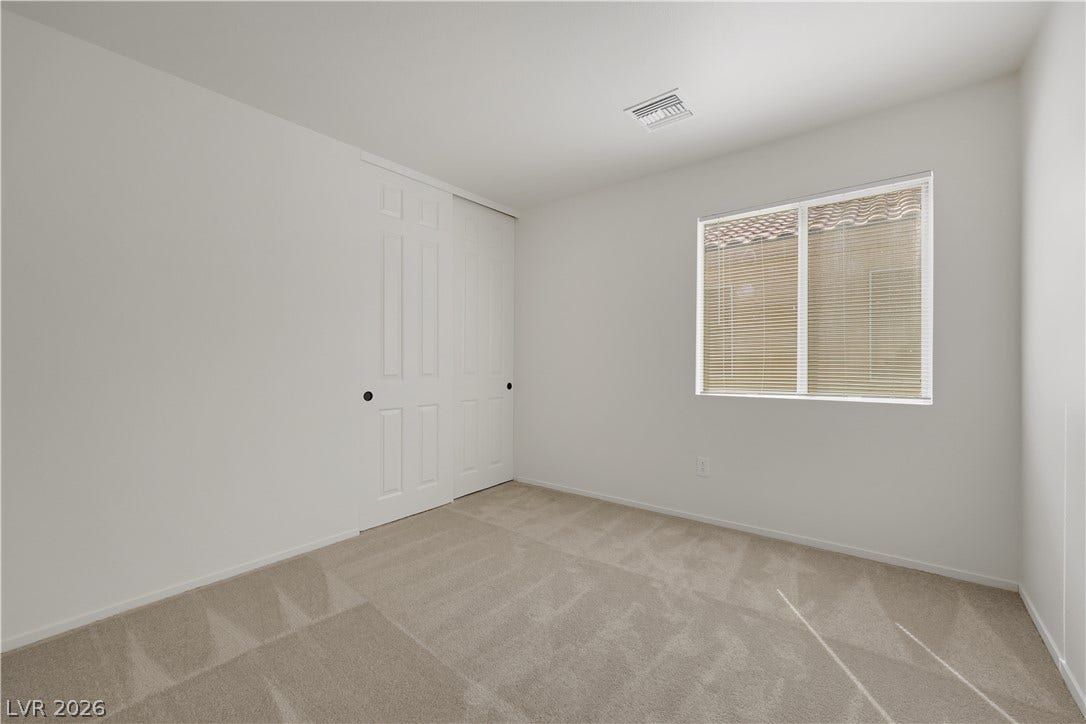 648 Moonlight Mesa Drive, Henderson, NV 89011 A well-lit bedroom features plush carpeting and a spacious closet with sliding doors.