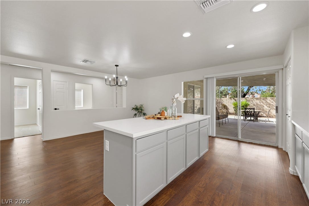 648 Moonlight Mesa Drive, Henderson, NV 89011 An inviting open-concept layout features rich hardwood flooring and a large kitchen island, connecting to a private patio through sliding glass doors.