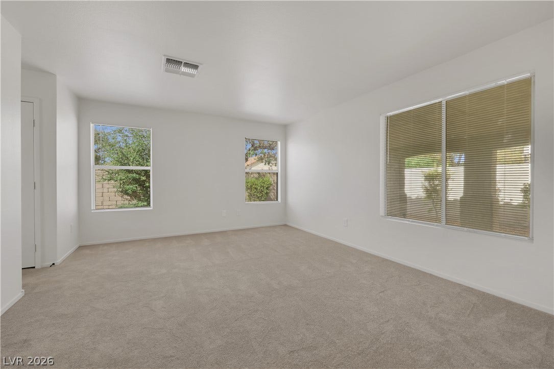 648 Moonlight Mesa Drive, Henderson, NV 89011 A spacious, naturally illuminated room featuring plush carpeting and large windows with privacy blinds.