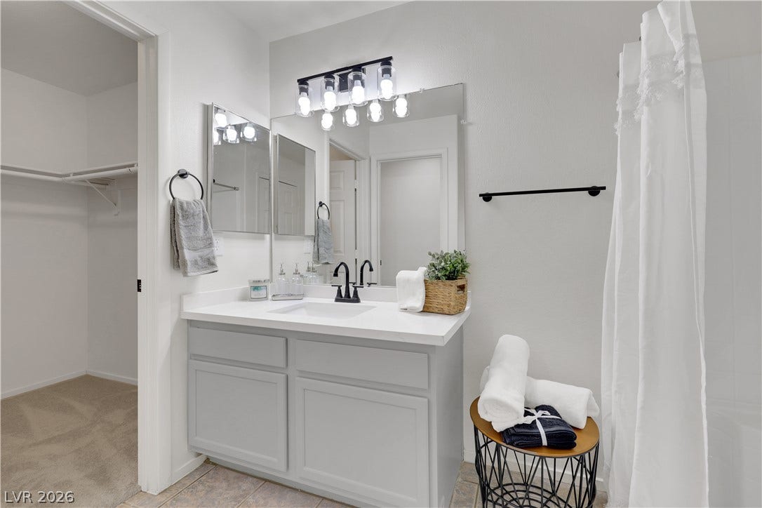 648 Moonlight Mesa Drive, Henderson, NV 89011 A well-appointed bathroom features a single vanity, sleek fixtures, and a shower with a privacy curtain.