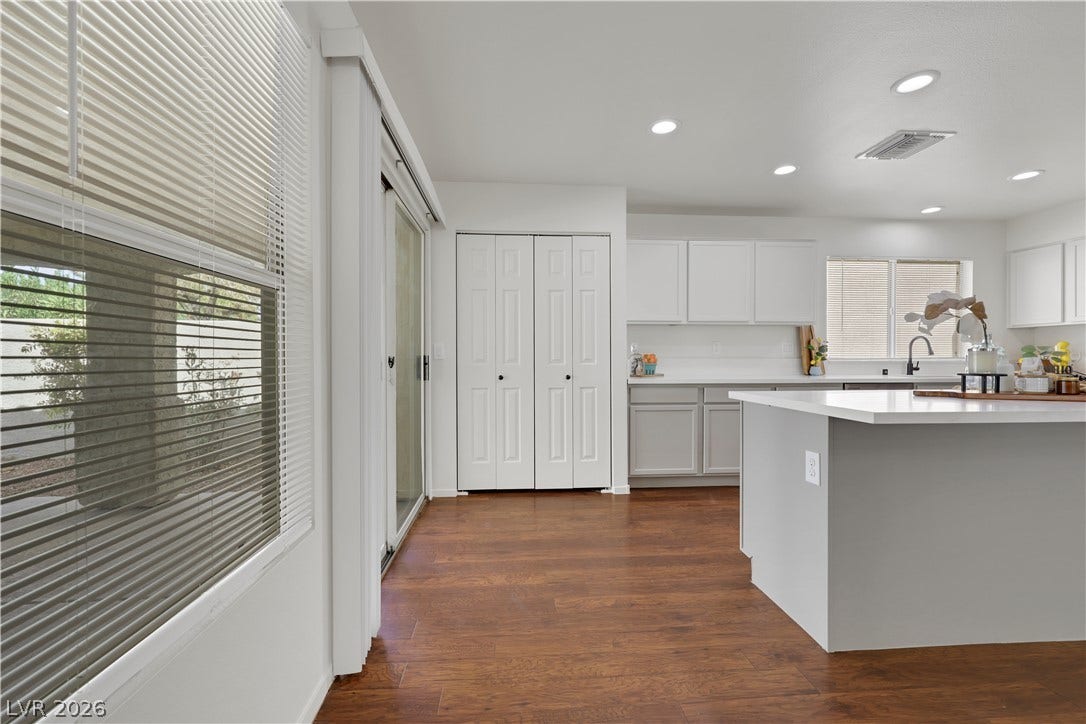 648 Moonlight Mesa Drive, Henderson, NV 89011 A well-lit kitchen with rich hardwood floors and sleek, white cabinetry offers abundant storage and prep space.