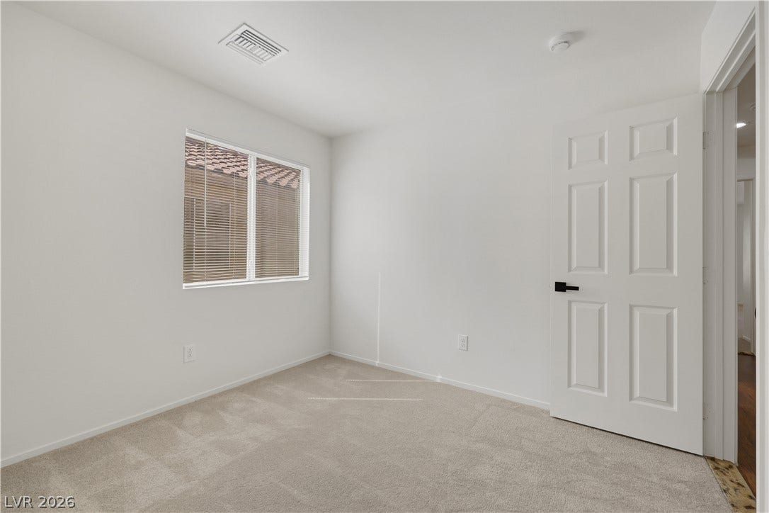 648 Moonlight Mesa Drive, Henderson, NV 89011 A well-lit bedroom features plush carpeting and window blinds, creating a comfortable living space.