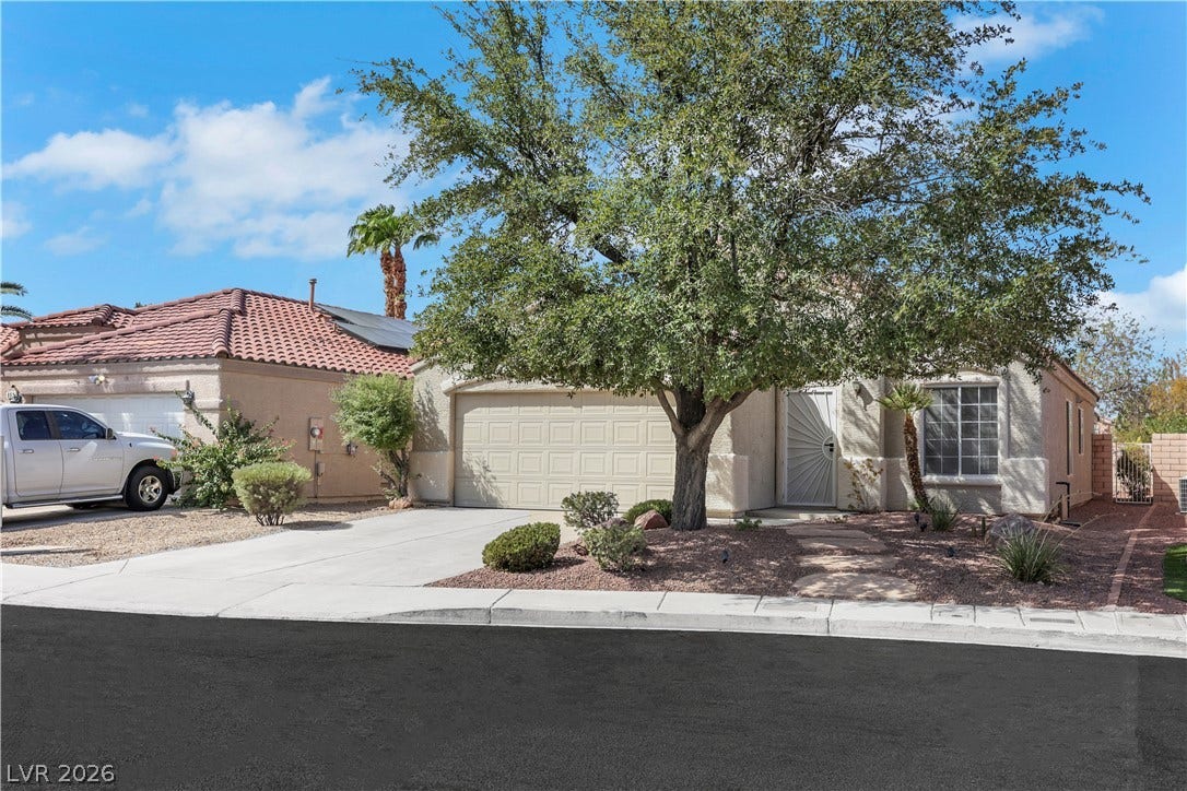 648 Moonlight Mesa Drive, Henderson, NV 89011 A neatly maintained desert-landscaped front yard with mature trees and practical concrete driveways.