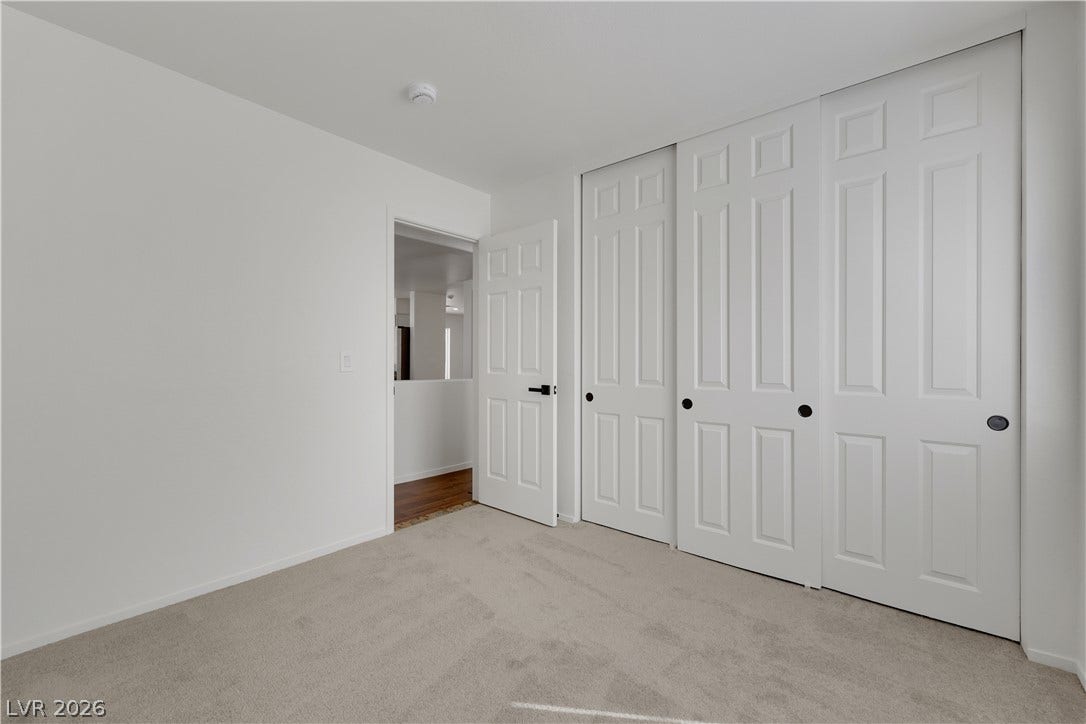 648 Moonlight Mesa Drive, Henderson, NV 89011 A well-lit bedroom features plush carpeting and convenient bi-fold closet doors, enhancing livability.