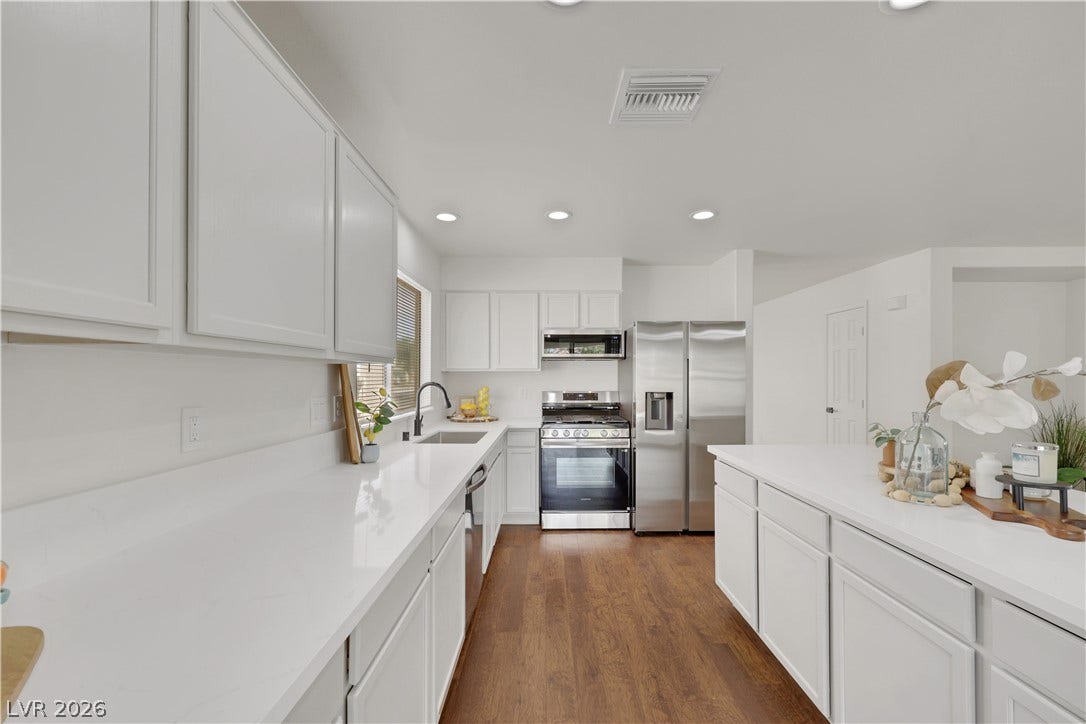 648 Moonlight Mesa Drive, Henderson, NV 89011 Gleaming wood flooring complements the bright, open-concept kitchen, featuring ample white cabinetry and a spacious island.