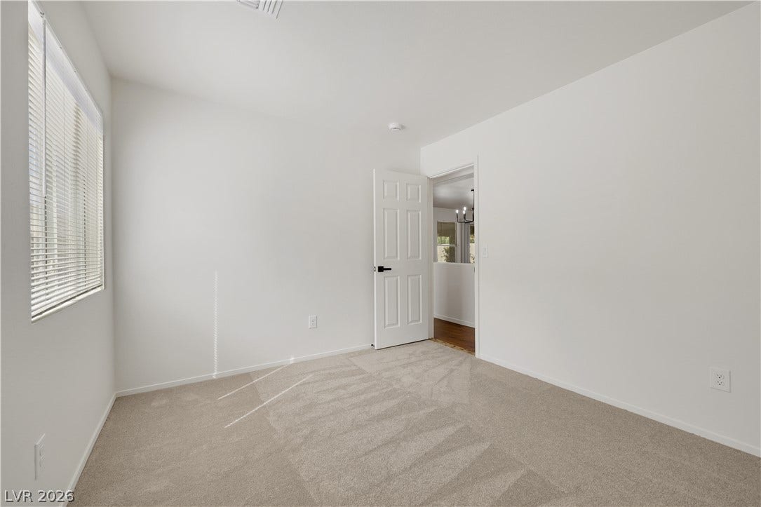 648 Moonlight Mesa Drive, Henderson, NV 89011 A well-lit room offers comfort and versatility, featuring neutral carpeting and a wide window.