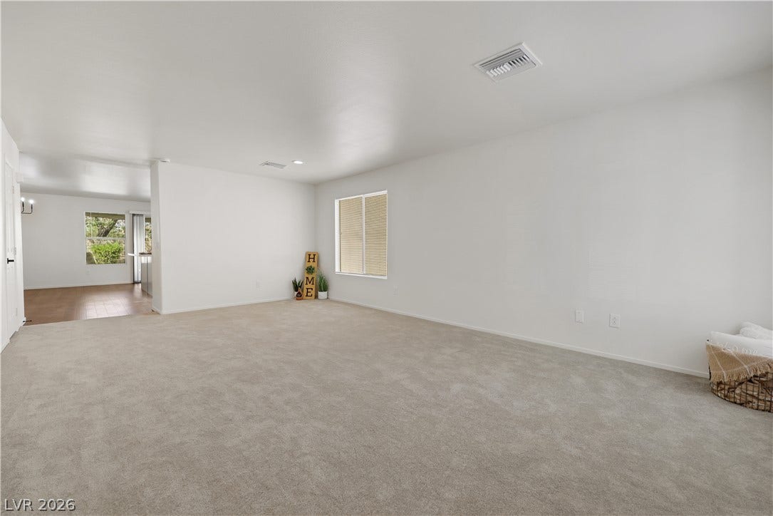 648 Moonlight Mesa Drive, Henderson, NV 89011 A spacious, naturally illuminated room features plush carpeting and a clear view to a separate area with wood flooring.