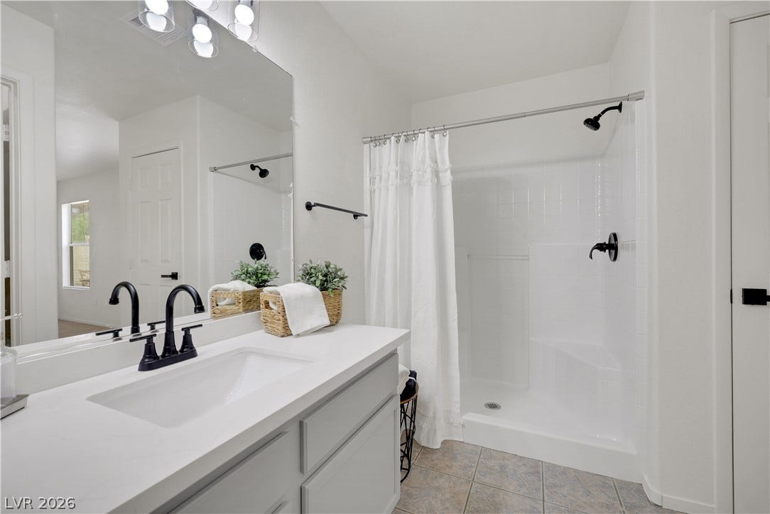 648 Moonlight Mesa Drive, Henderson, NV 89011 A well-lit bathroom features a modern vanity with a single sink and a bright, functional shower area.