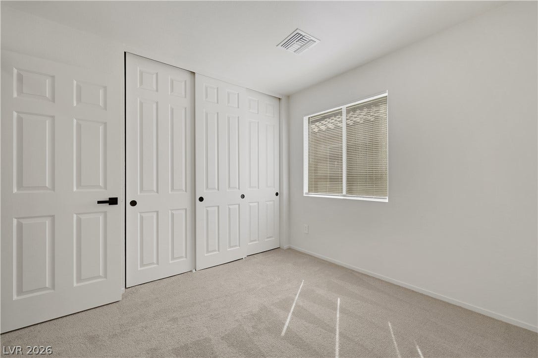 648 Moonlight Mesa Drive, Henderson, NV 89011 A well-lit bedroom provides ample storage with large sliding closet doors and neutral carpeting.