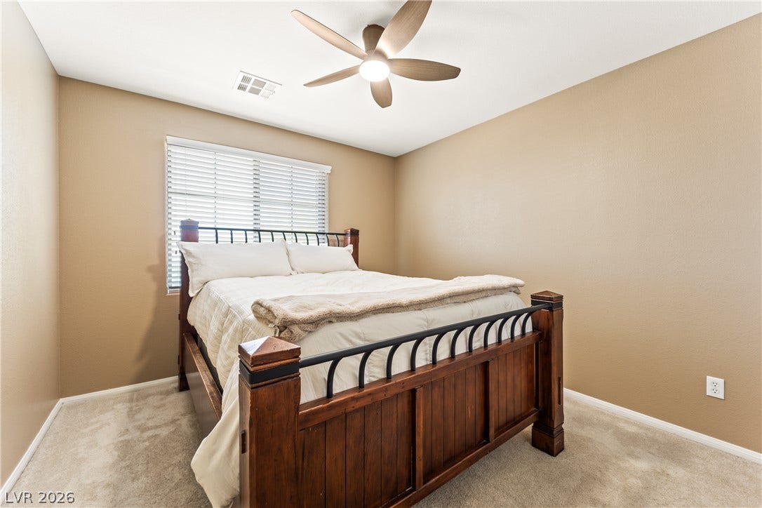 7337 Picnic Hill Street, Las Vegas, NV 89166 A comfortable bedroom with soft carpeting and a contemporary ceiling fan, offering a serene personal retreat.