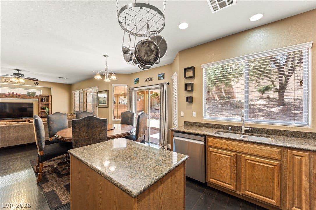 7337 Picnic Hill Street, Las Vegas, NV 89166 An inviting kitchen with rich wood cabinetry and granite countertops, seamlessly connects to a welcoming dining area.