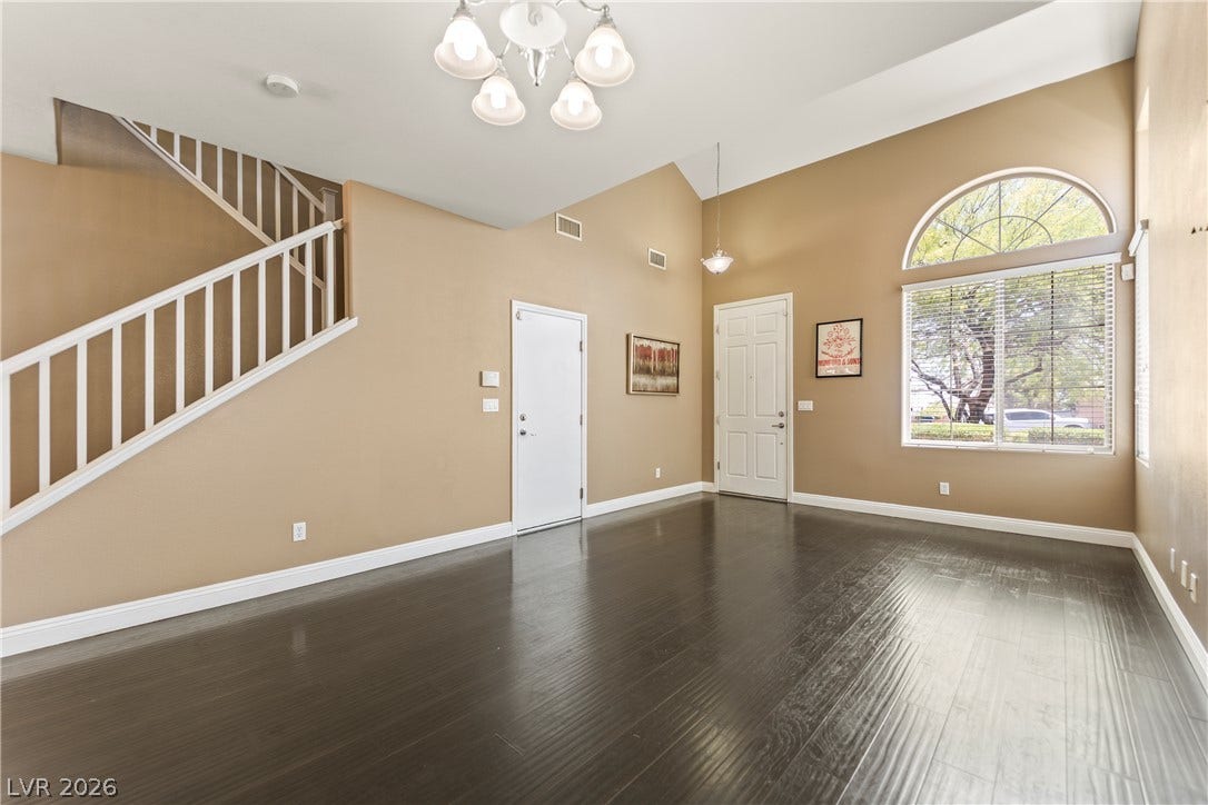 7337 Picnic Hill Street, Las Vegas, NV 89166 Rich Laminate floors complement soaring ceilings and an arched window, creating an inviting living space.