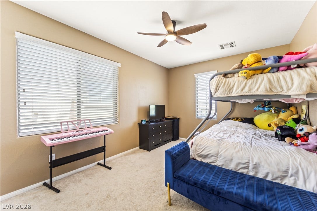7337 Picnic Hill Street, Las Vegas, NV 89166 Comfortable bedroom with neutral walls and soft carpet flooring, illuminated by a modern ceiling fan with lighting.