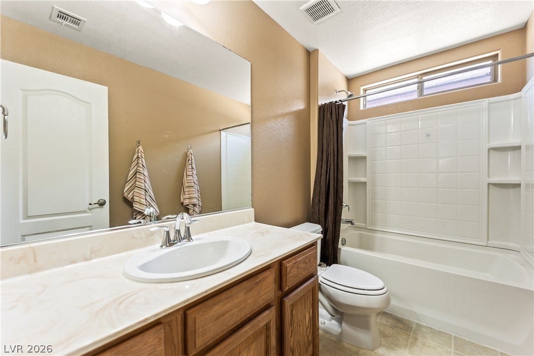 7337 Picnic Hill Street, Las Vegas, NV 89166 A compact bathroom featuring a full vanity, an integrated tub and shower combination, and a window above the bath for natural illumination.
