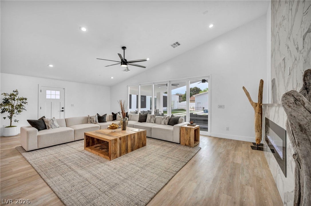 3630 Tobias Lane, Las Vegas, NV 89120 A spacious living area features high ceilings, a contemporary fireplace, and a wall of glass doors opening to the outside.