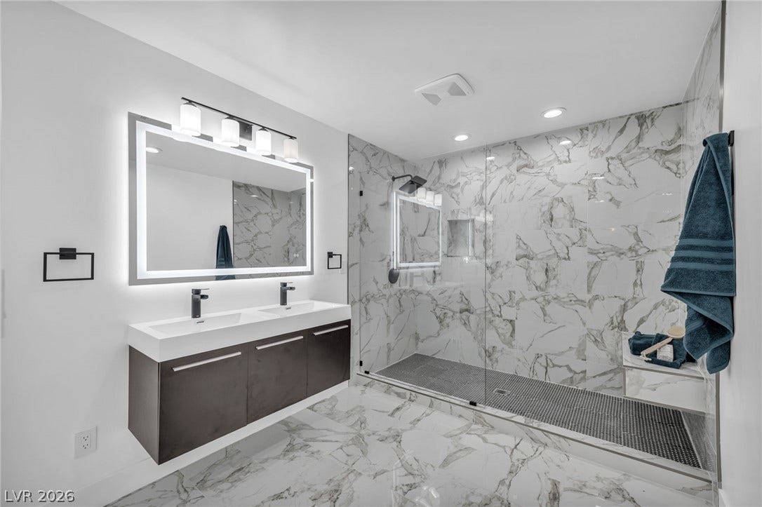 3630 Tobias Lane, Las Vegas, NV 89120 A well-appointed bath features a dual vanity and an expansive glass-enclosed shower with luxurious marble-patterned tile.