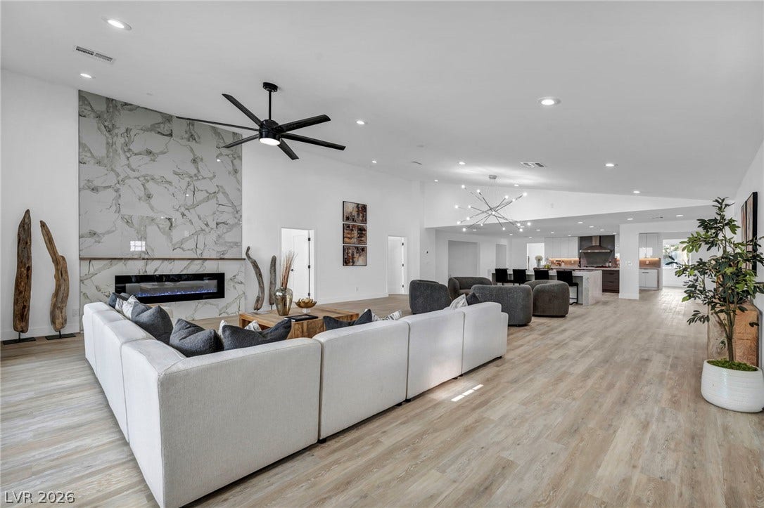 3630 Tobias Lane, Las Vegas, NV 89120 An airy living space features a striking marble fireplace and light wood-look flooring, extending to a modern kitchen with a large island.