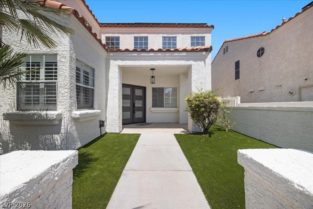 8024 Shorecrest Drive, Las Vegas, NV 89128 A striking facade with a grand entryway invites you into this welcoming abode, featuring a well-maintained artificial turf lawn.