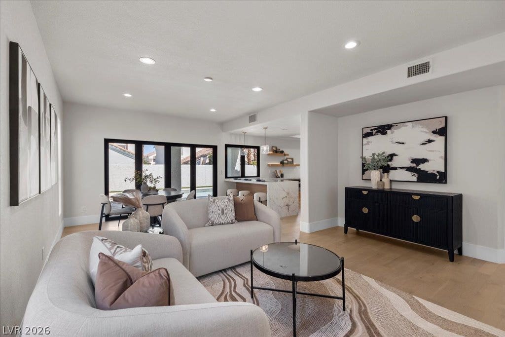 8024 Shorecrest Drive, Las Vegas, NV 89128 Recessed lighting illuminates an inviting open-concept living area with lustrous hardwood floors and a striking view of the dining space and kitchen.