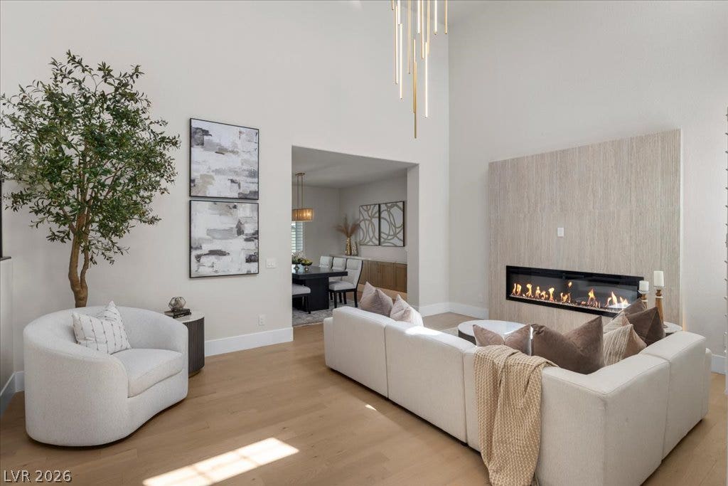 8024 Shorecrest Drive, Las Vegas, NV 89128 A chic living space boasts towering ceilings, a sleek modern fireplace, and rich hardwood floors.
