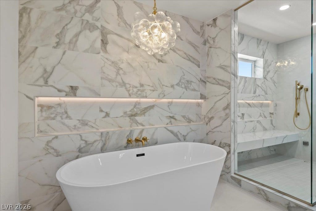 8024 Shorecrest Drive, Las Vegas, NV 89128 A lavish bath space showcases a freestanding soaking tub, a sleek glass-enclosed shower, and illuminated shelving.