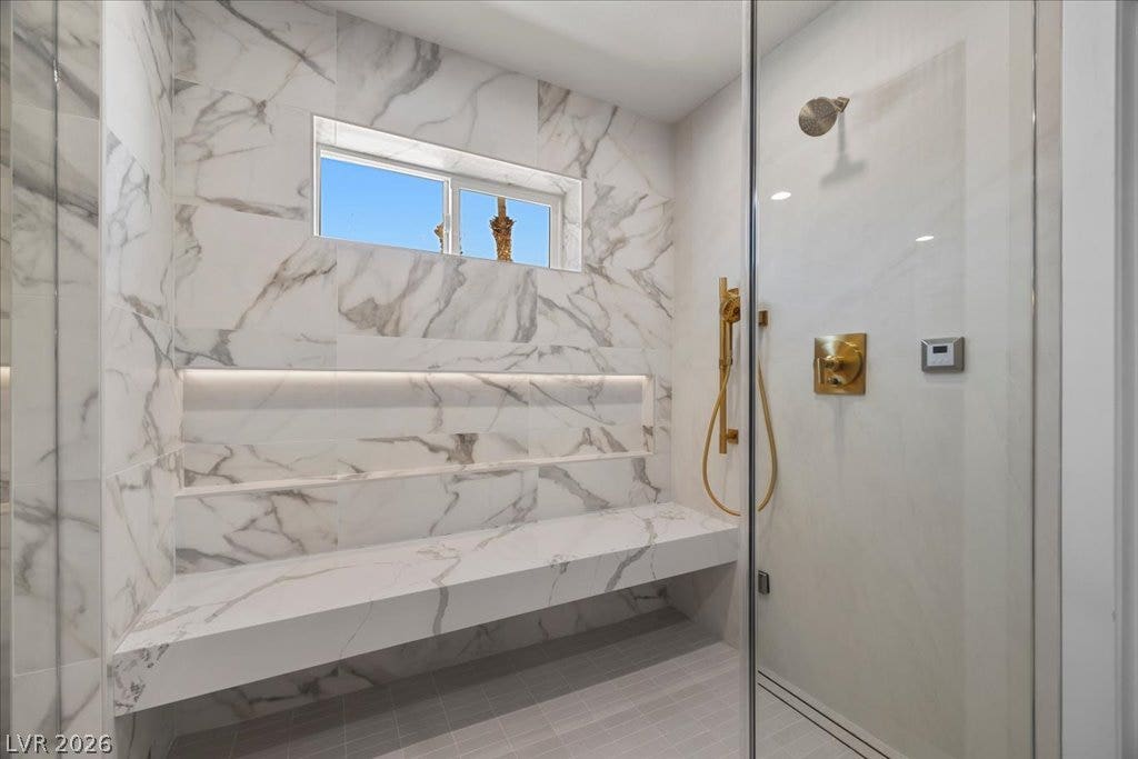 8024 Shorecrest Drive, Las Vegas, NV 89128 Marble-tiled shower with built-in bench seating and a window for natural light.