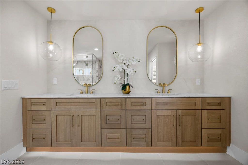 8024 Shorecrest Drive, Las Vegas, NV 89128 A refined bathroom features a dual vanity with elegant gold fixtures and luminous pendant lighting.