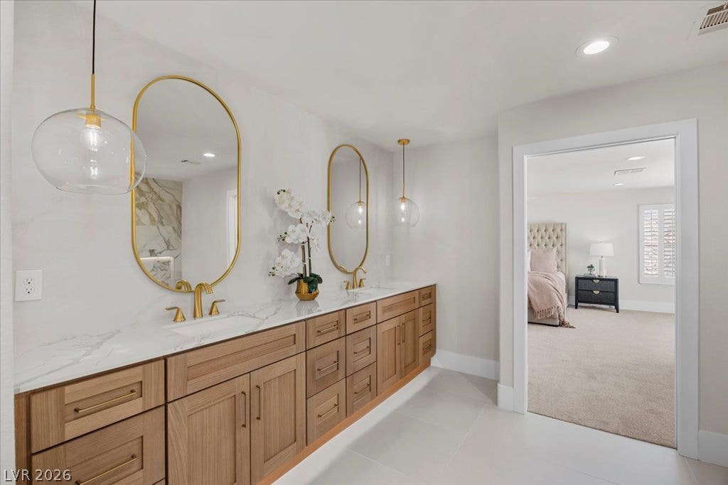 8024 Shorecrest Drive, Las Vegas, NV 89128 Double vanity with sleek gold fixtures and modern lighting defines this luxurious primary bathroom.
