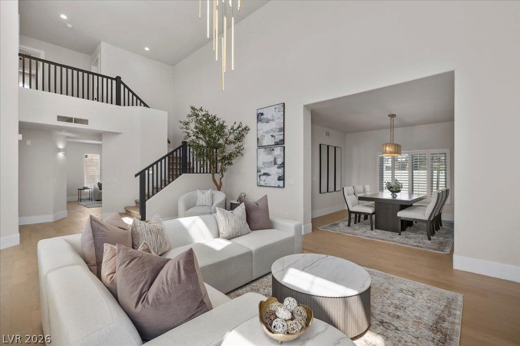 8024 Shorecrest Drive, Las Vegas, NV 89128 A grand two-story living area features a modern chandelier, a prominent staircase, and an adjacent dining space.