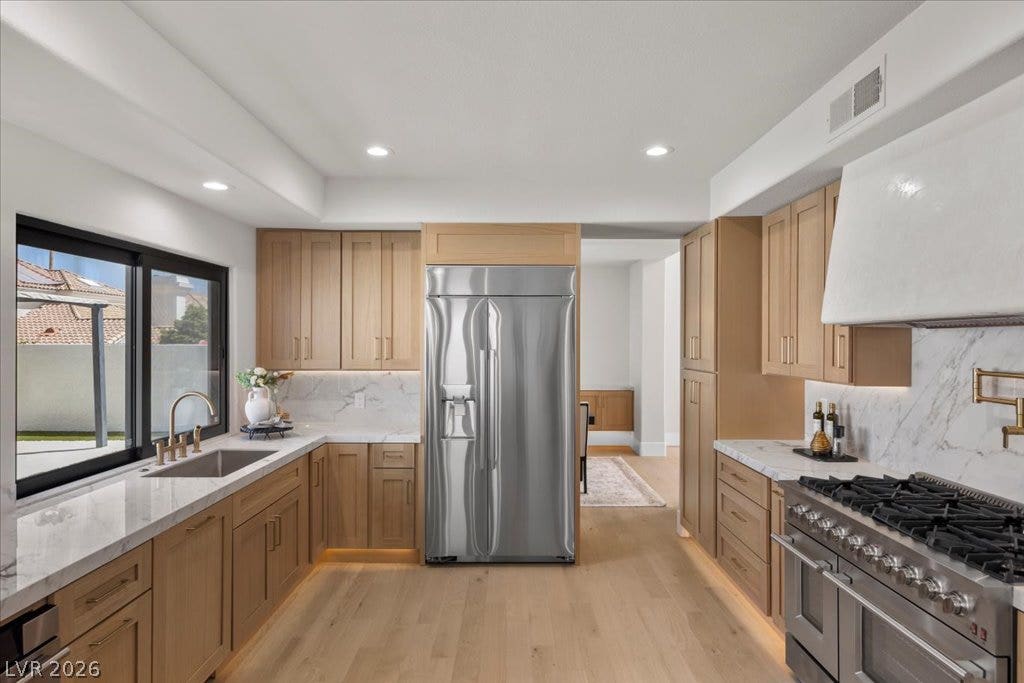 8024 Shorecrest Drive, Las Vegas, NV 89128 Culinary aspirations meet elegant design in this well-appointed kitchen featuring light wood cabinetry and lustrous stone countertops.
