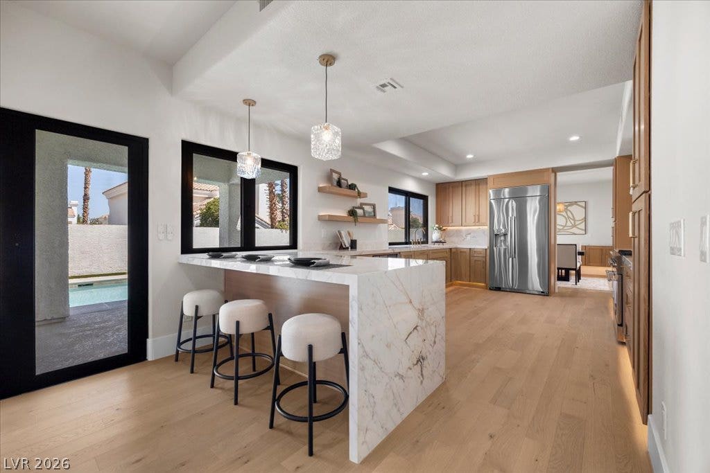 8024 Shorecrest Drive, Las Vegas, NV 89128 A gourmet kitchen offers rich wood cabinetry, stainless steel appliances, and a beautiful marble-topped island with seating.