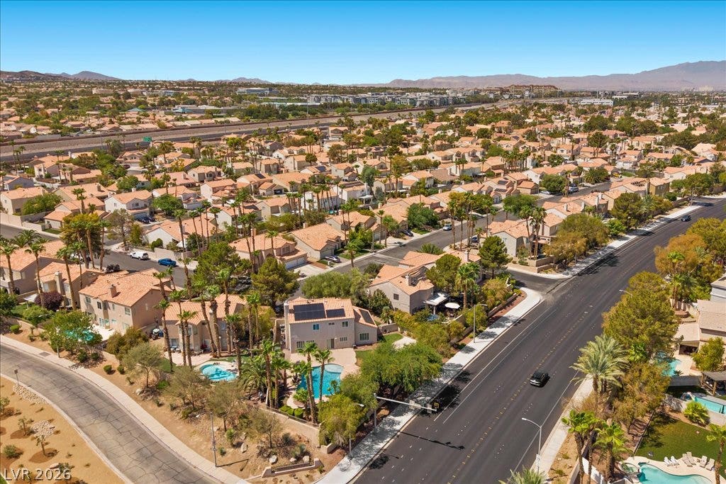 2000 Silverton Drive, Henderson, NV 89074 An aerial perspective showcases a residential neighborhood with numerous homes featuring terracotta roofs and lush palm trees, hinting at a community rich with amenities.